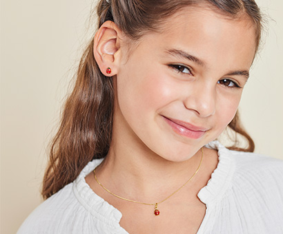Goldener Schmuck für Mädchen mit Marienkäfer Motiv Mädchen trägt goldenen Schmuck mit Marienkäfer Motiv