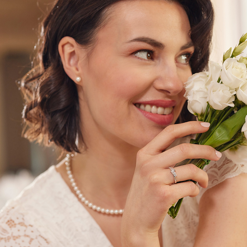 Braut trägt silbernen Ring und Perlenschmuck